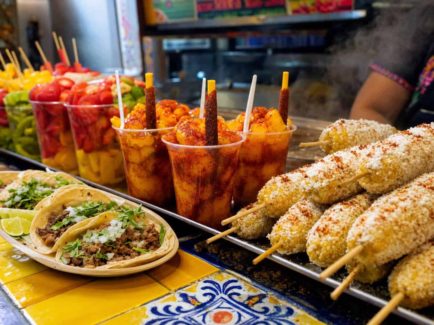 Cups of elote, tacos, and drinks from a food stall at Harry Hines Bazaar in Dallas