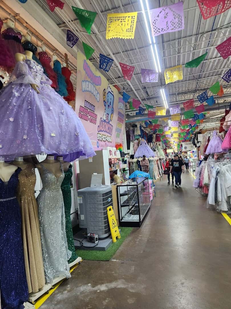 Quinceanera and formal gowns on display along an aisle at Harry Hines Bazaar in Dallas