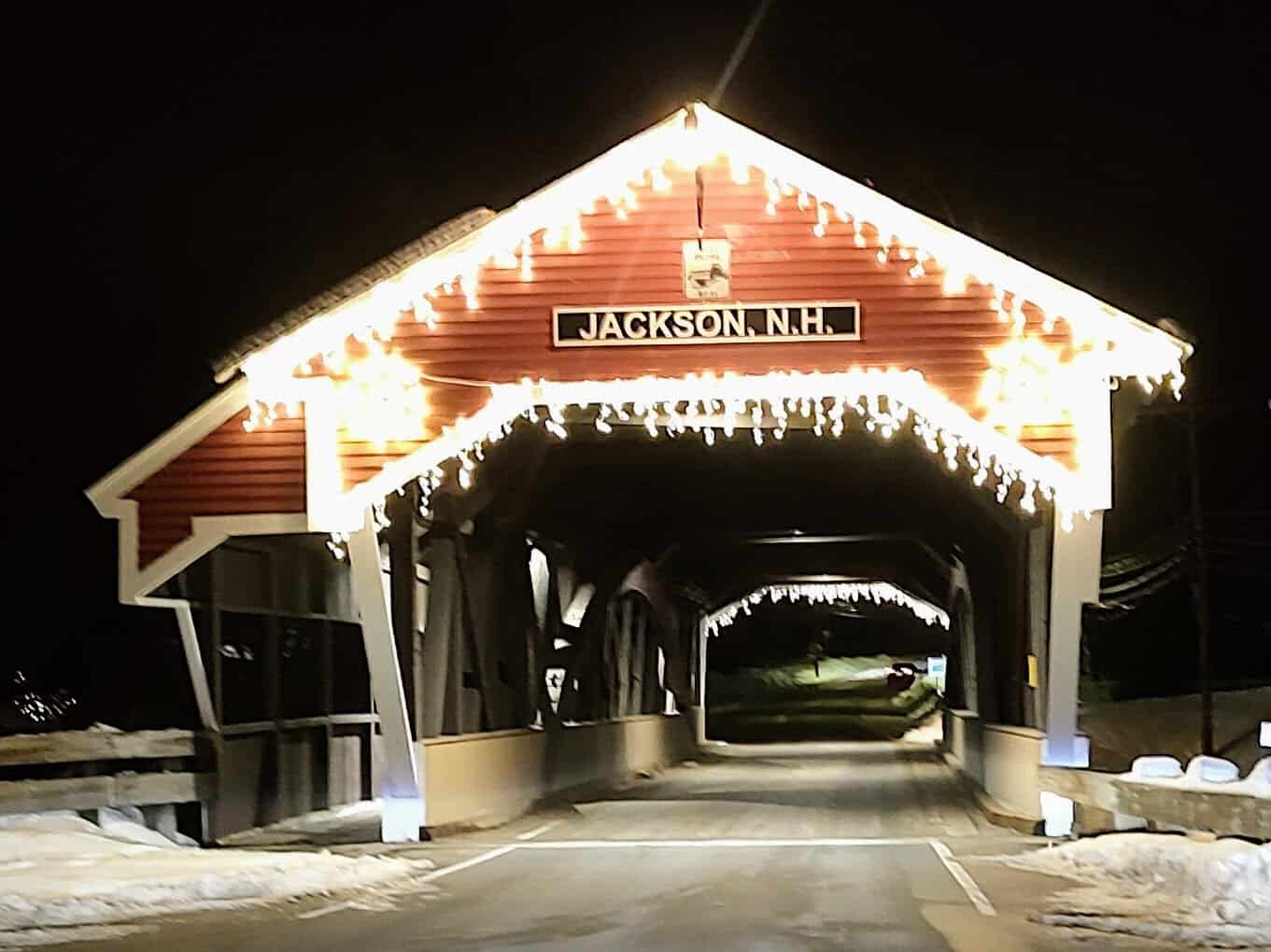 Red Honeymoon covered bridge lit at night with snow, Jackson, New Hampshire