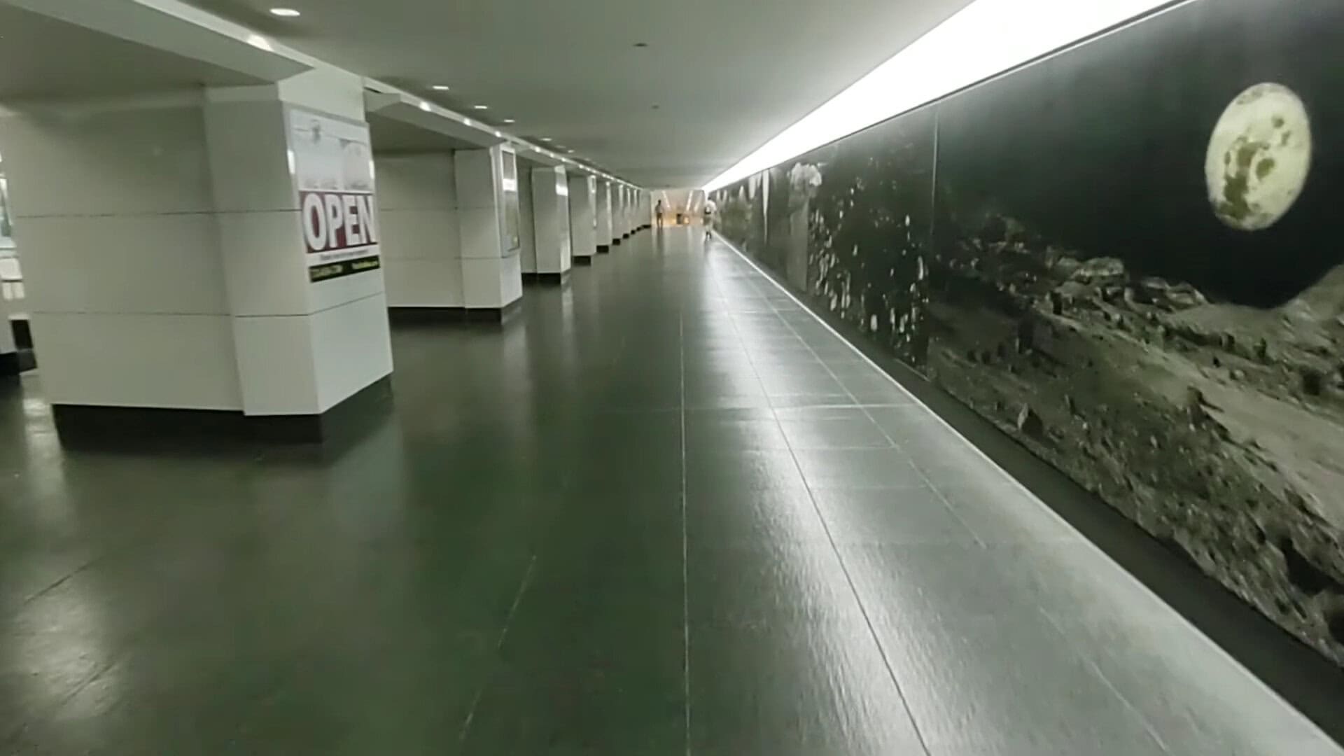 Long tunnel walkway with a lunar mural in downtown Houston