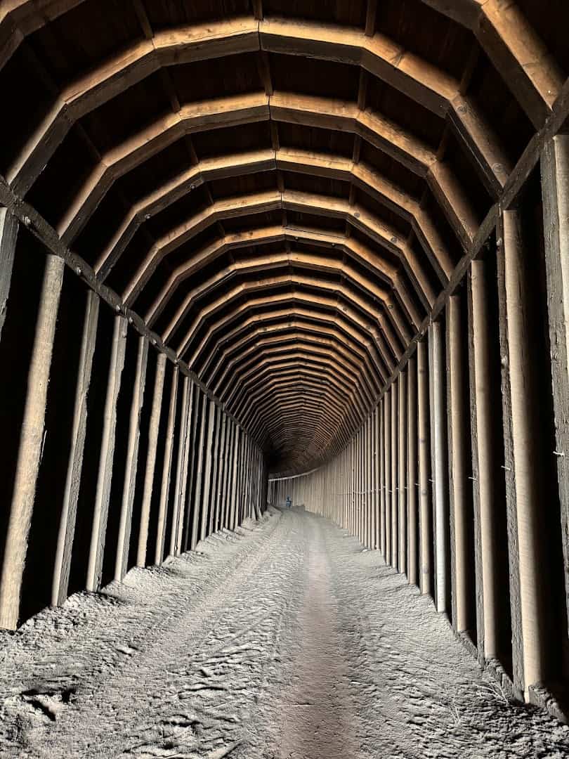 Inside Clarity Tunnel looking toward the distant circle of daylight through timber framing, Caprock Canyons, Texas