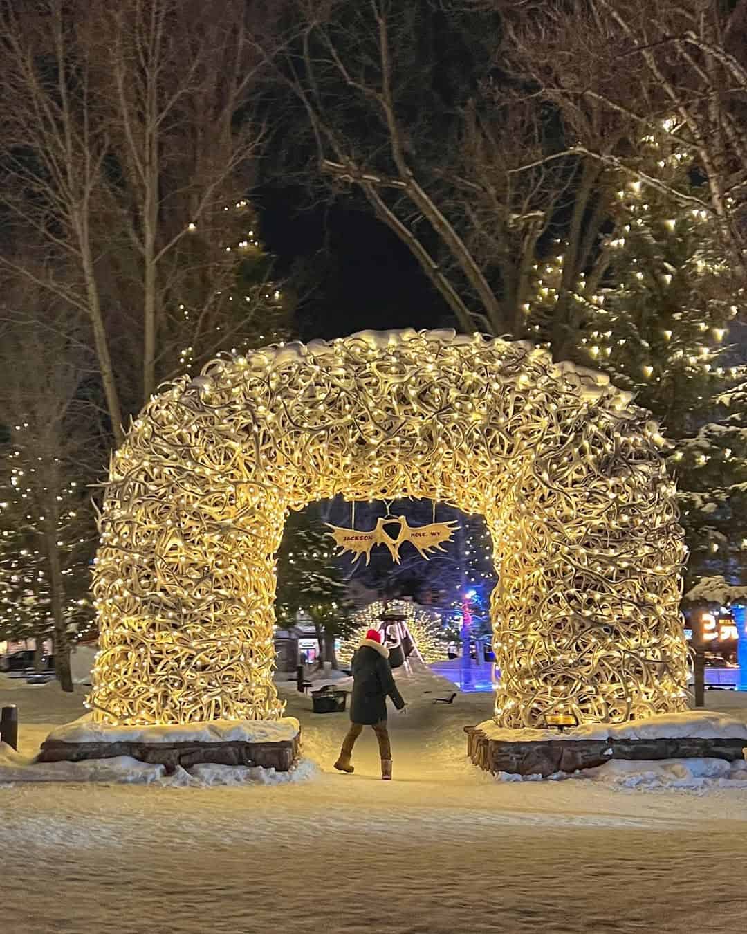 Elk-antler arch wrapped in white holiday lights over snow at Jackson Town Square in Jackson, Wyoming