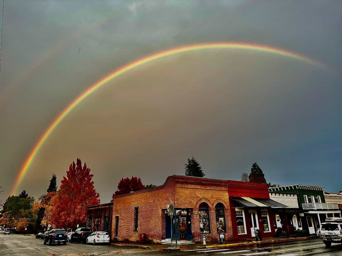 Historic brick storefront with an orange autumn tree on California Street, Jacksonville, Oregon
