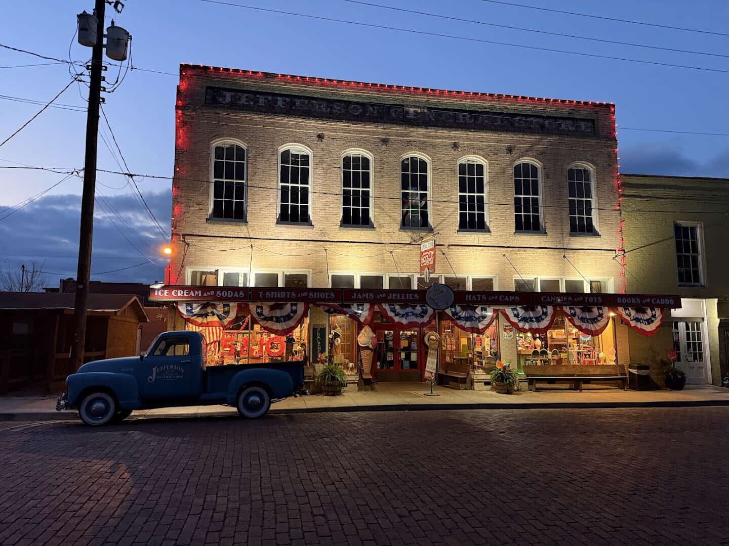A historic downtown storefront and vintage truck on the brick street in Jefferson, Texas