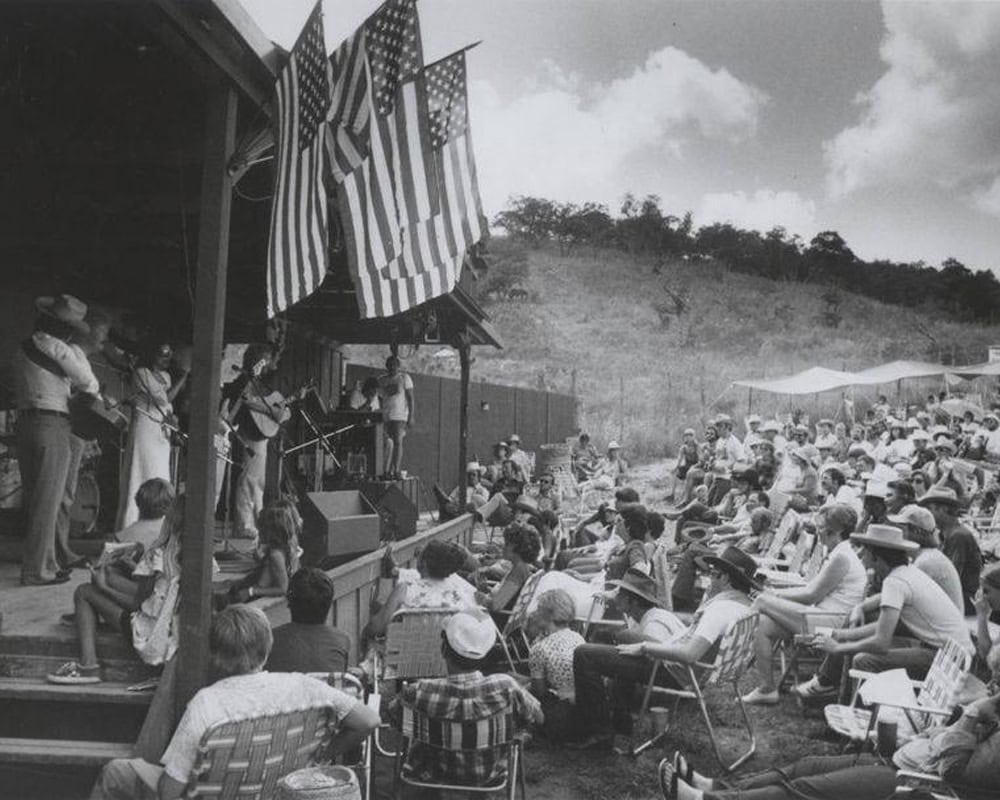 Vintage photo of the Kerrville Folk Festival with musicians and a crowd on the hillside
