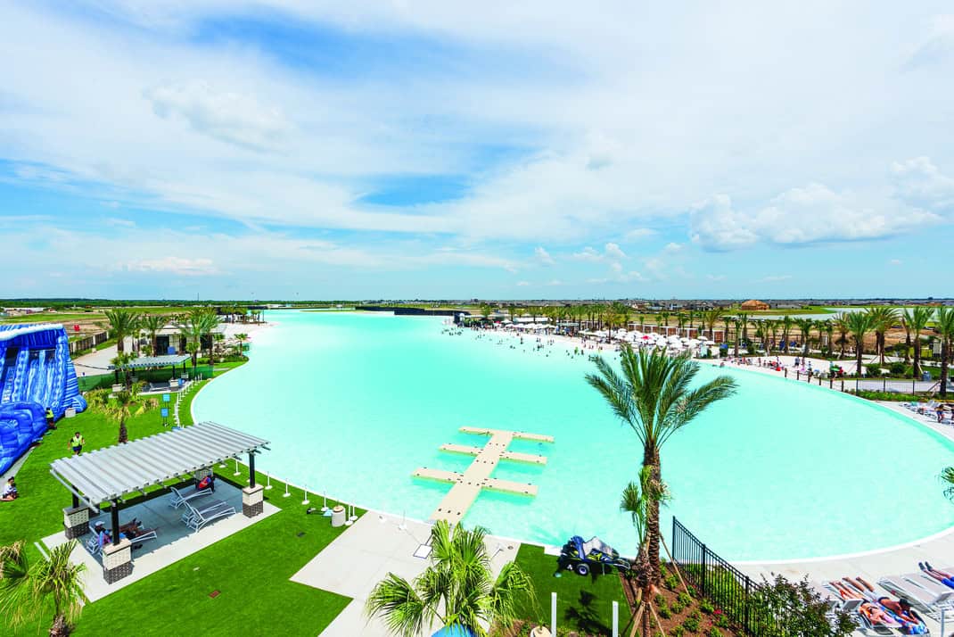 The turquoise Crystal Lagoon with a swim-out dock and white sand beach at Lago Mar in Texas City