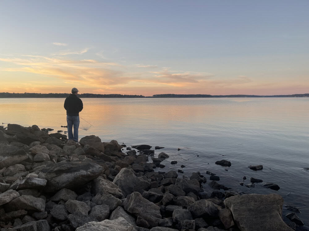 Angler fishing from the shore at sunset on Lake O' the Pines, Texas