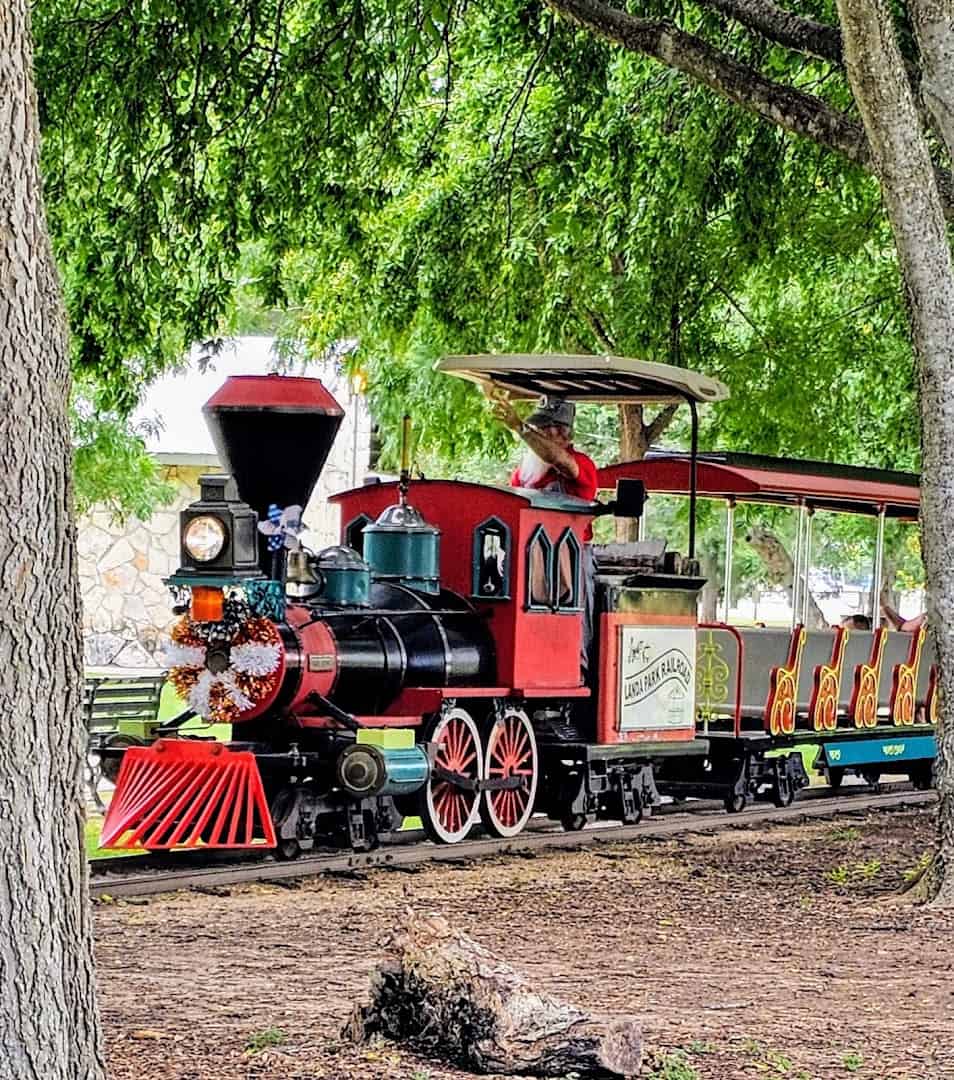 Red miniature train running through the trees at Landa Park