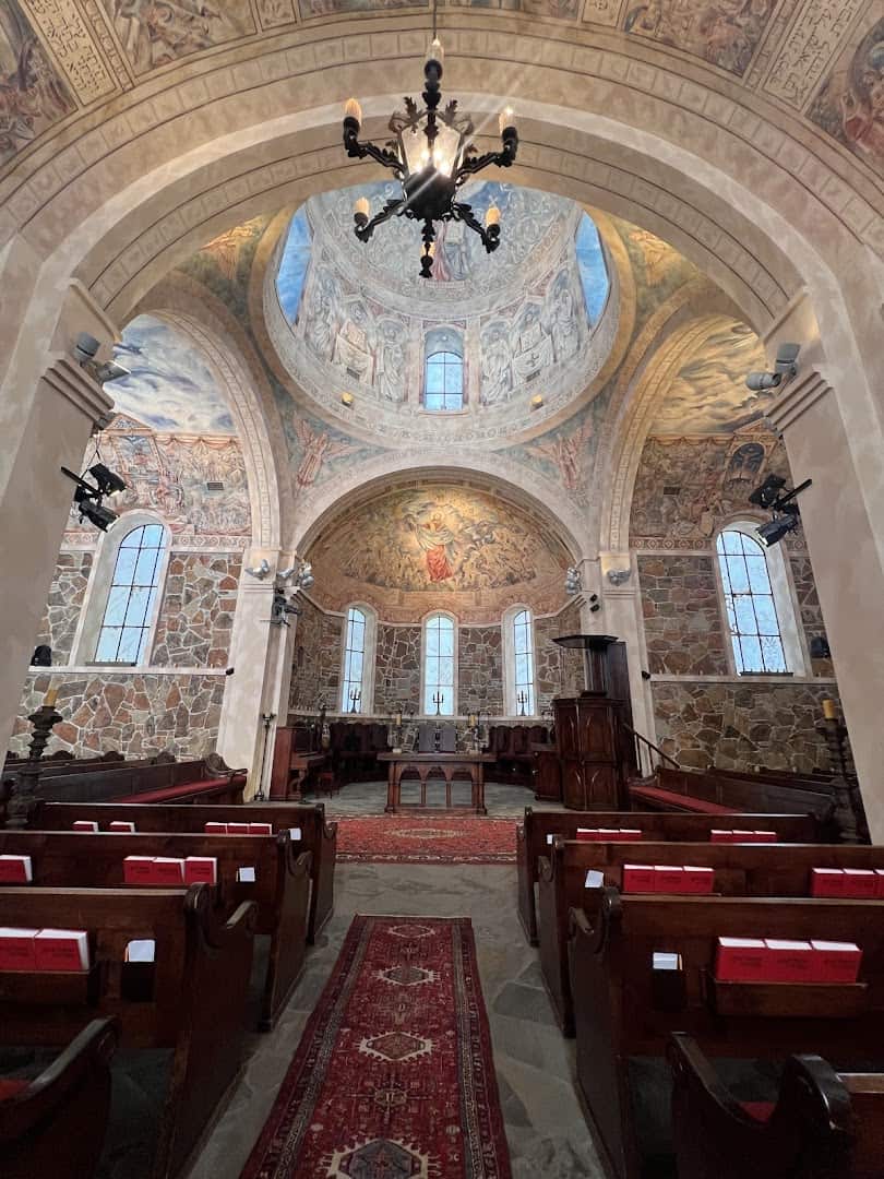 Inside the Byzantine Stone Chapel at the Lanier Theological Library, with painted dome, pews and stone walls
