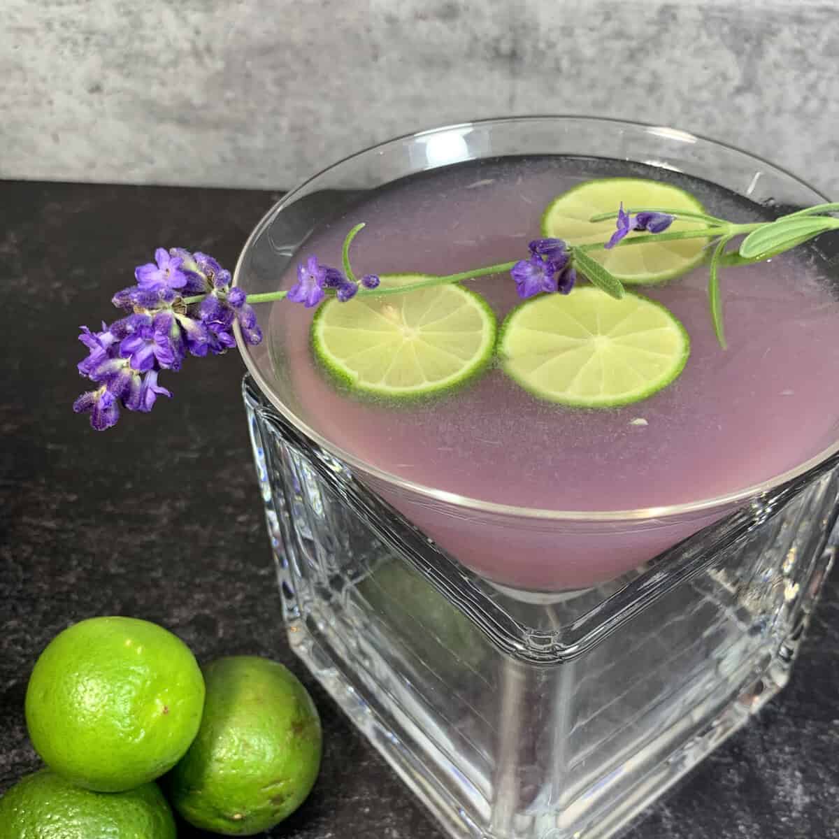 A purple lavender cocktail garnished with lime and fresh lavender