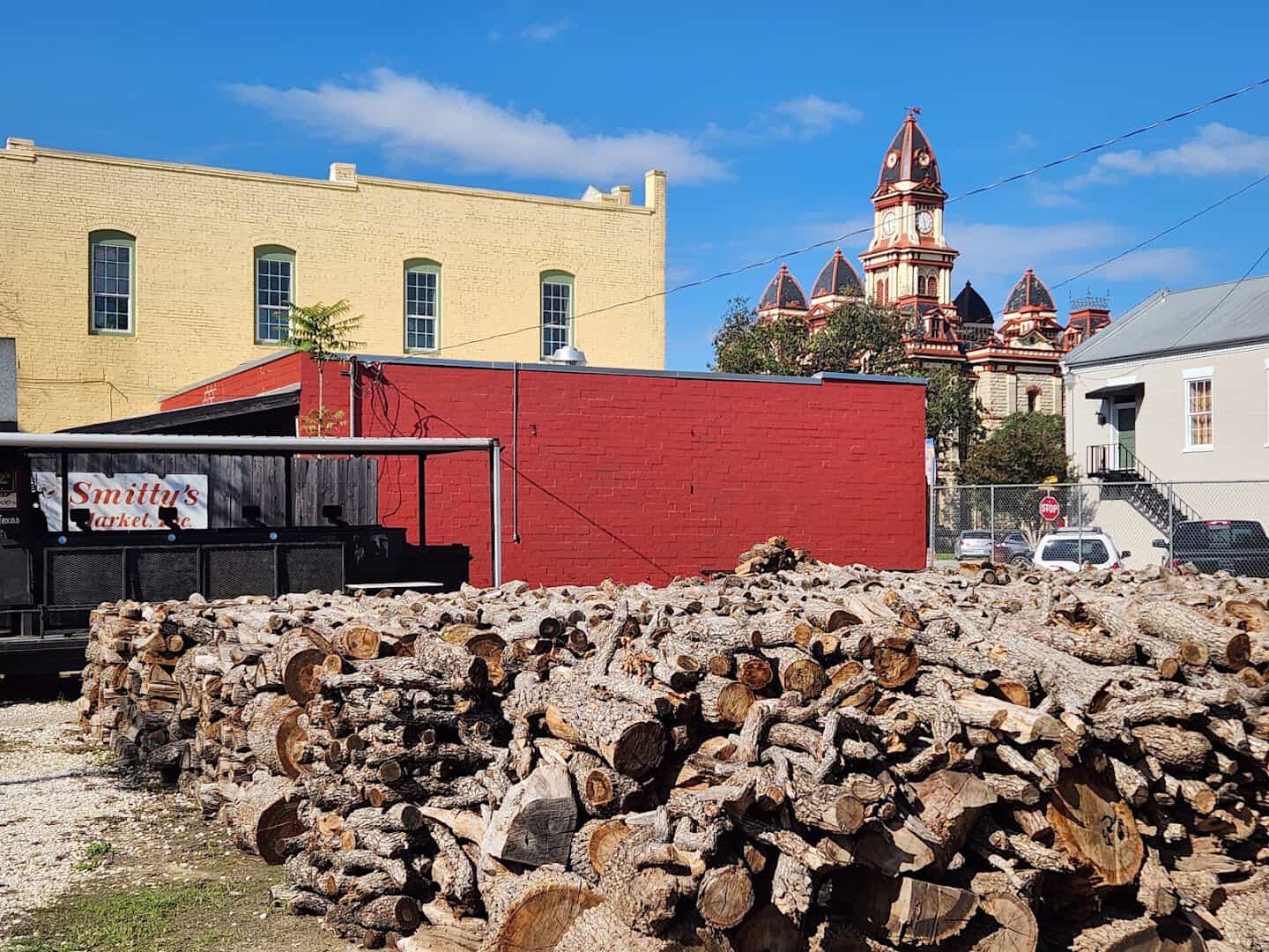 Stacked firewood with the Caldwell County Courthouse behind in Lockhart, Texas
