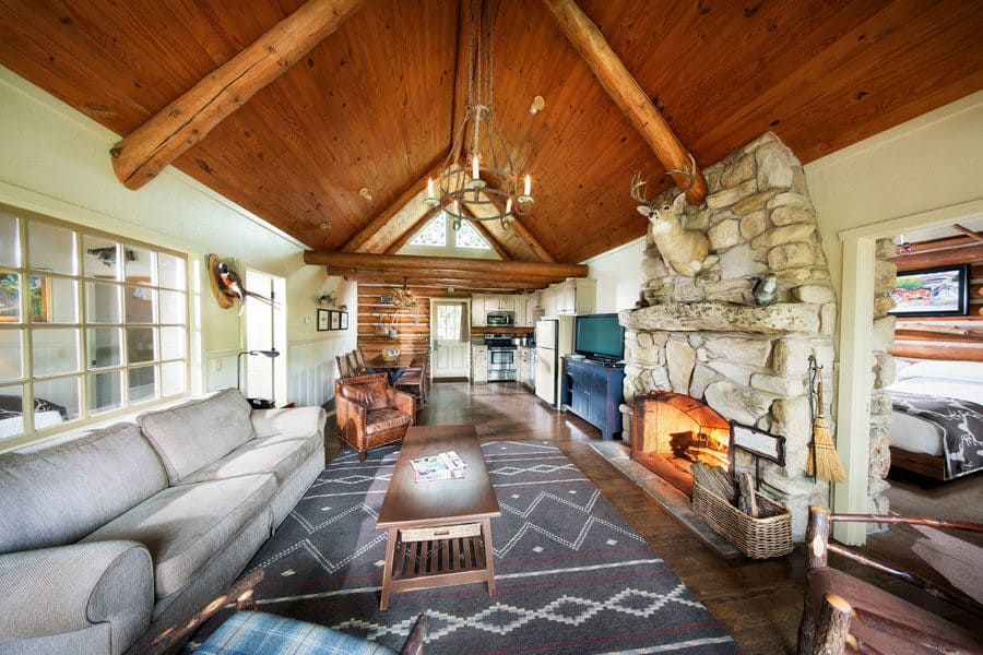 A log cabin living room with a lit stone fireplace at Big Cedar Lodge, Ridgedale, Missouri
