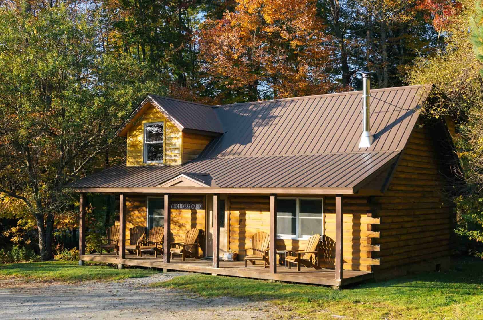 A log cabin with a covered porch in autumn woods at Sterling Ridge Resort, Jeffersonville, Vermont