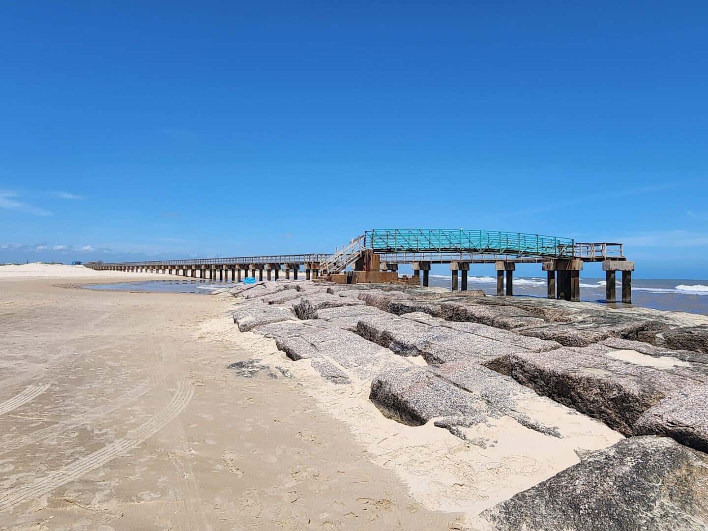 Rock jetty and fishing pier where the Colorado River reaches the Gulf at Matagorda Beach, Texas