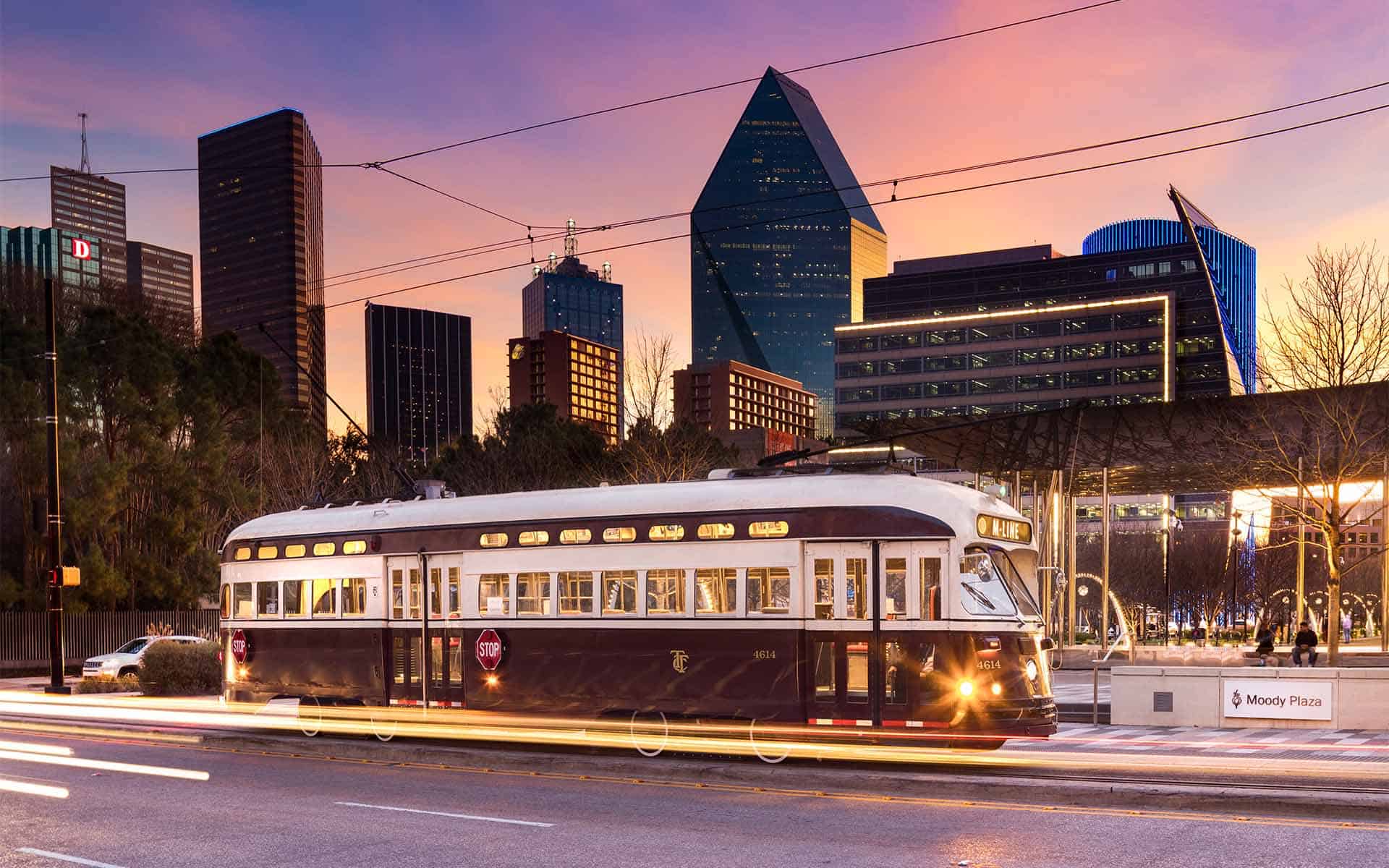 McKinney Avenue Trolley streetcar with the Dallas skyline at sunset