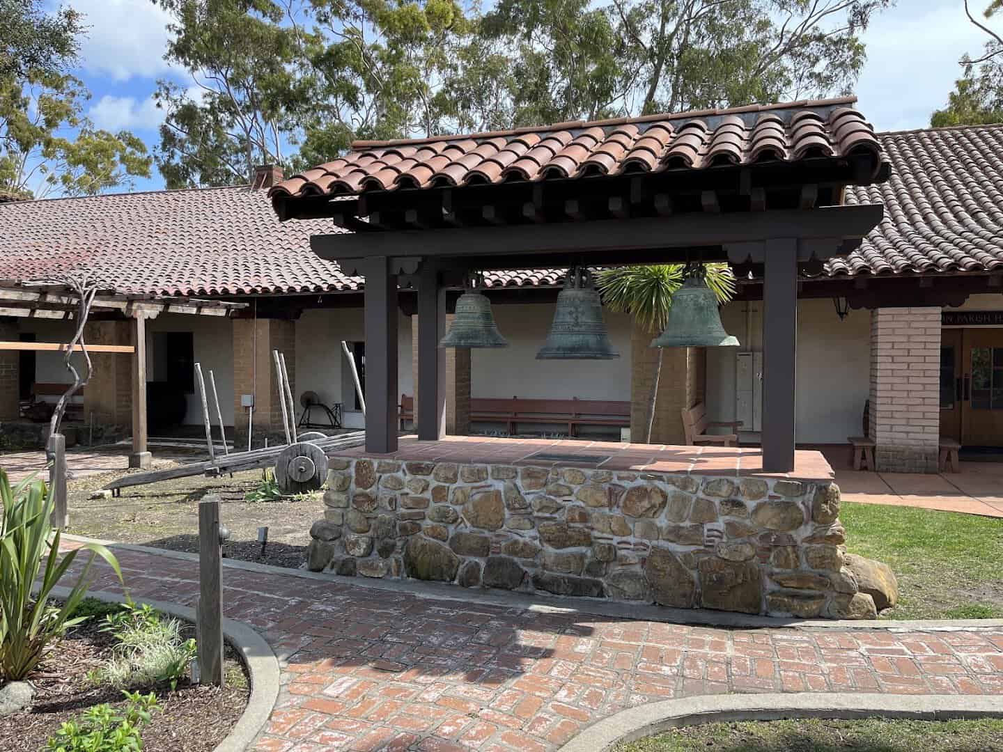 Mission bells and adobe courtyard under blue sky at Mission San Luis Obispo, California