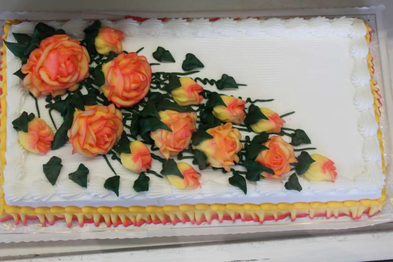 A white sheet cake decorated with icing roses at Moeller's Bakery in Houston