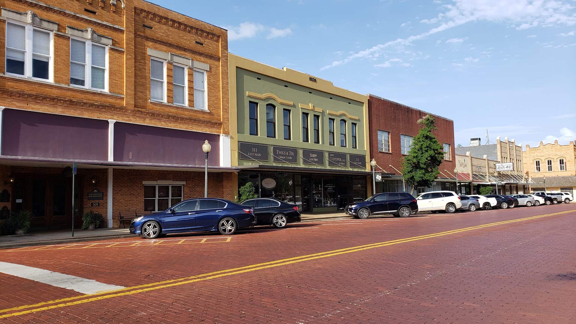 Row of two story brick storefronts along the red brick Main Street in downtown Nacogdoches
