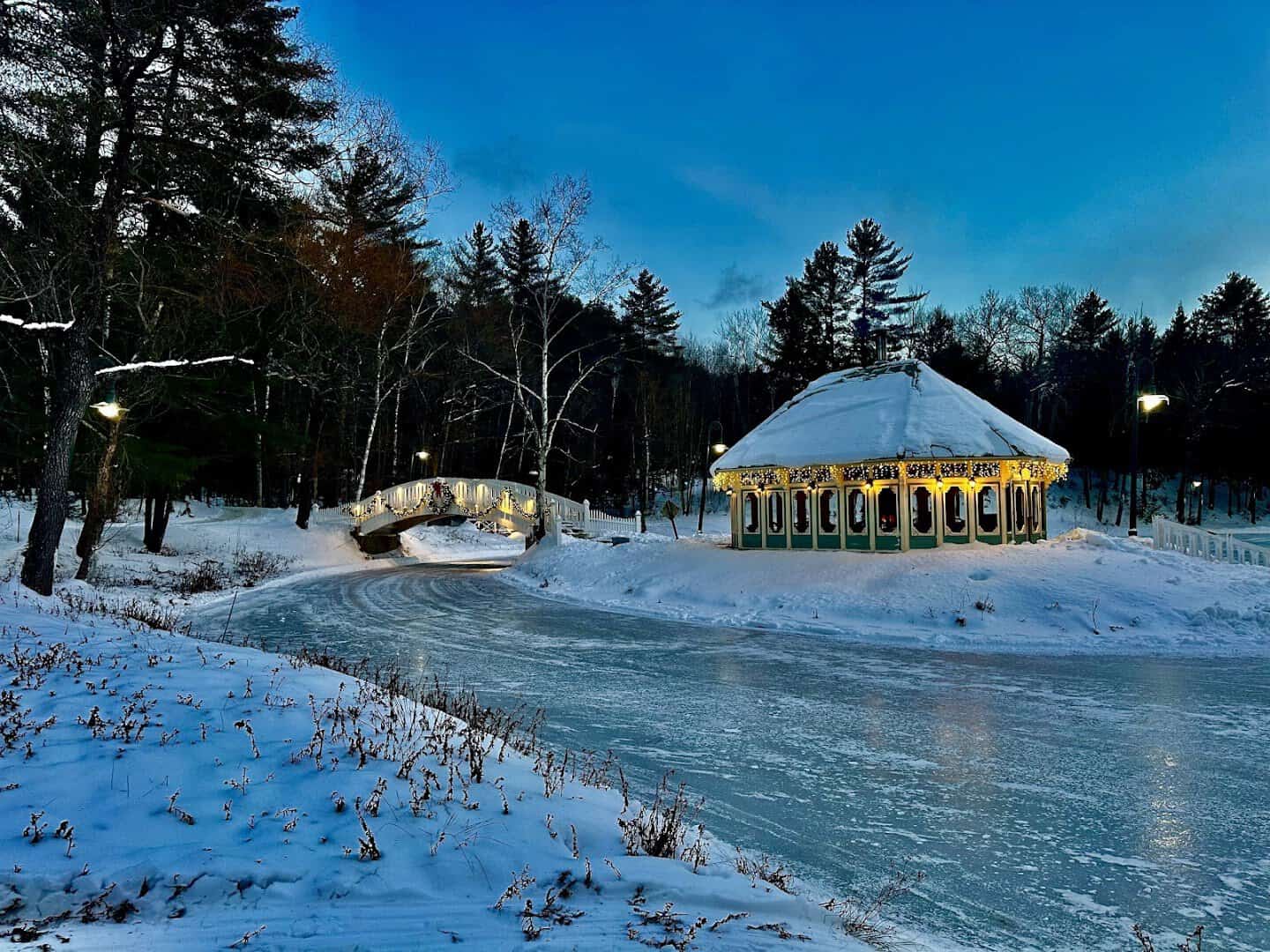 The lit gazebo and frozen skating pond at Nestlenook Farm on a snowy evening, Jackson, New Hampshire
