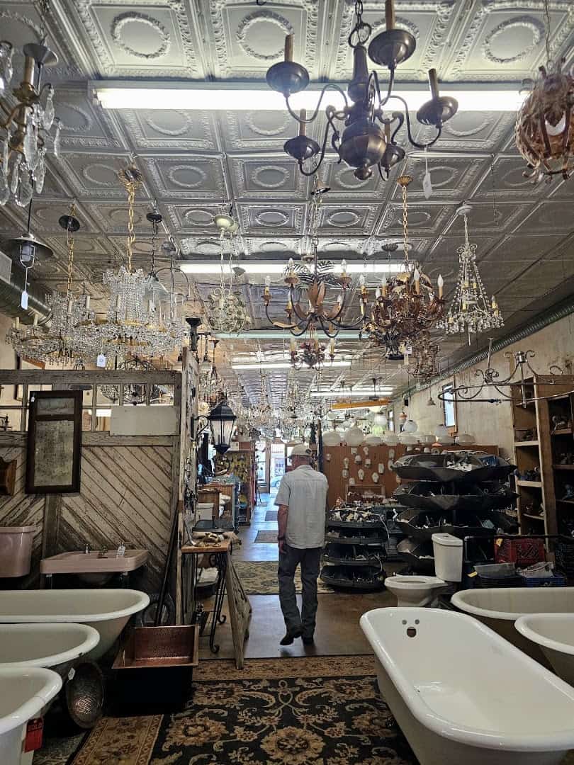 Aisle of salvaged doors, chandeliers and a clawfoot tub inside Old Home Supply House in Fort Worth