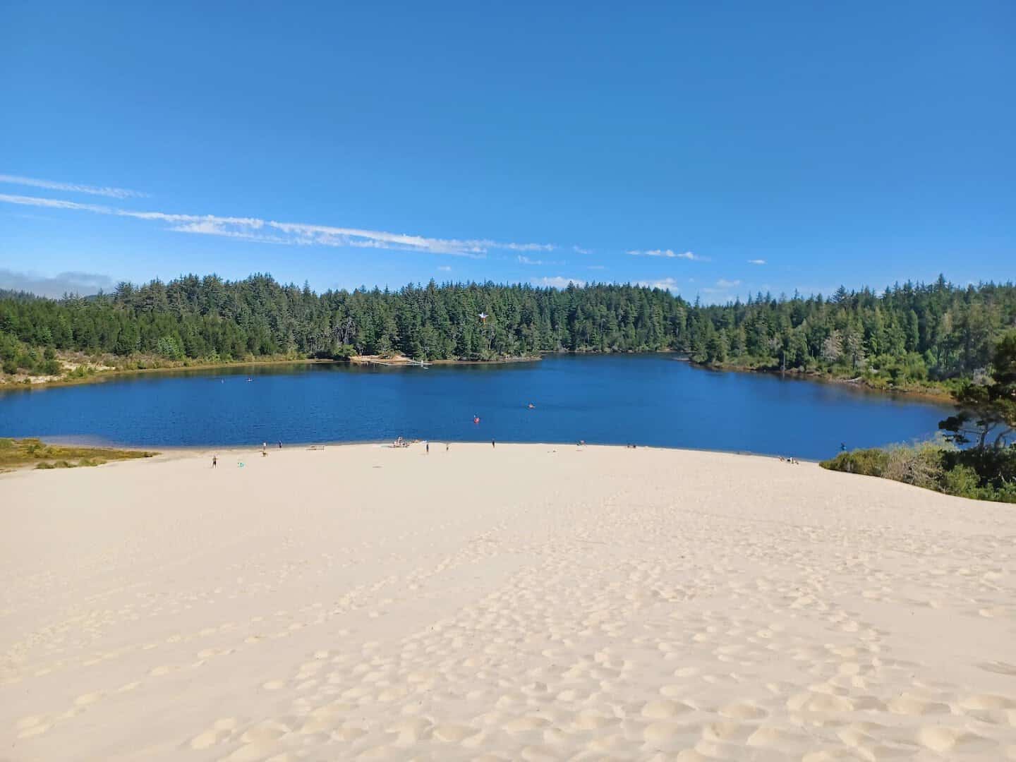 White sand dunes sweeping down to a forest-ringed lake at the Oregon Dunes near Reedsport