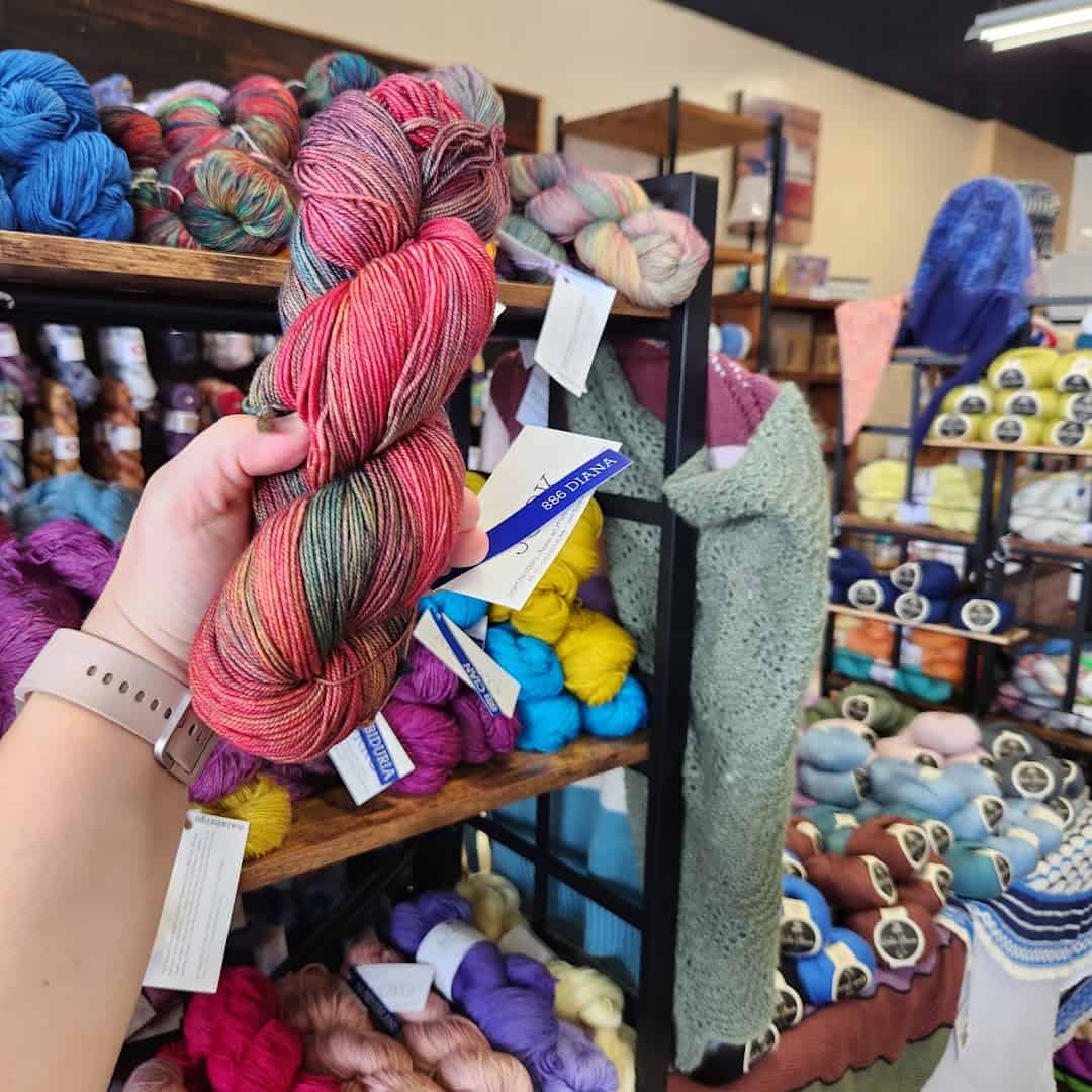 A hand holding a pink hand-dyed skein of yarn at Lone Star Yarn in Bedford, Texas