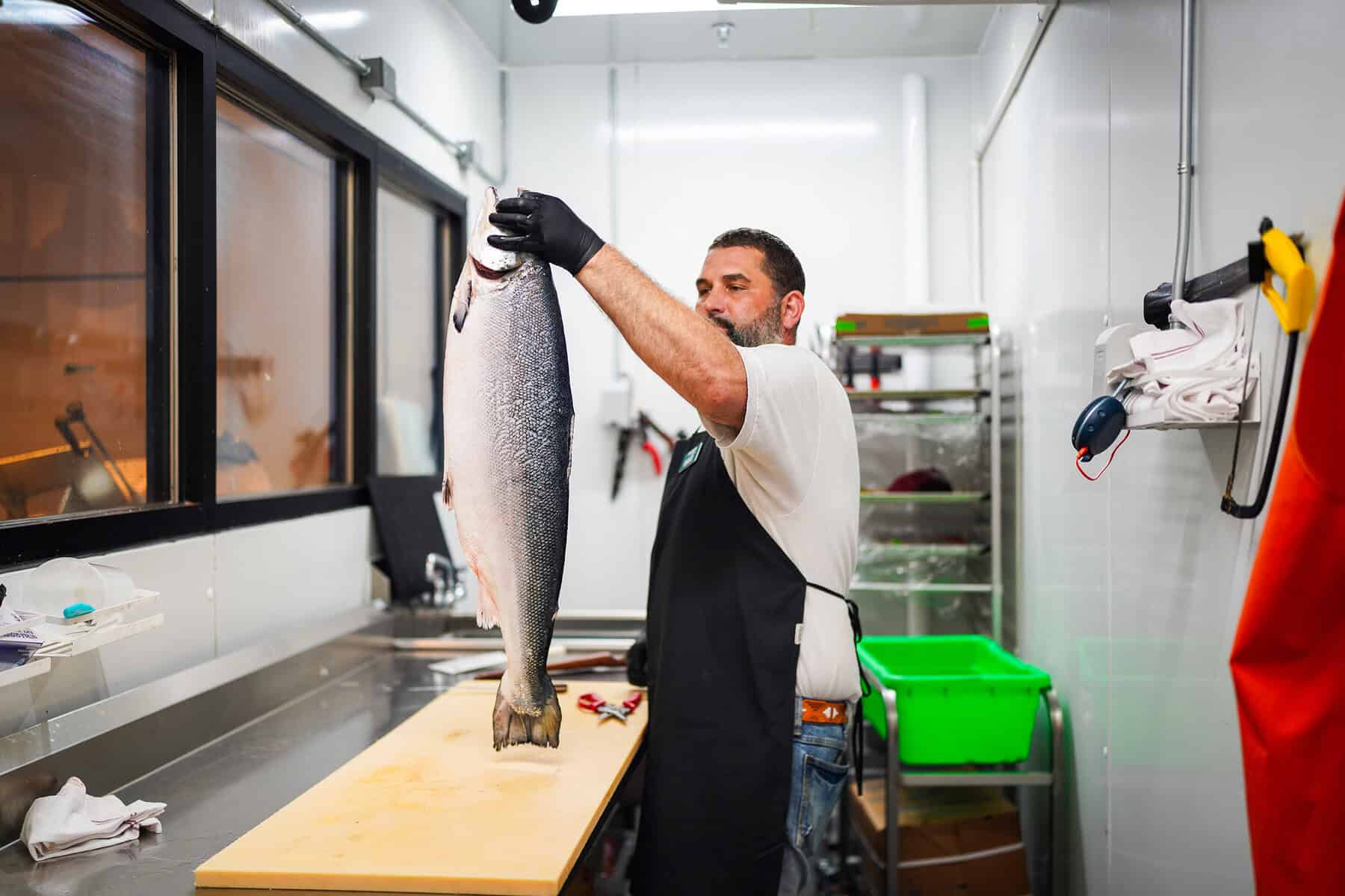 A butcher holds a whole fresh salmon in Pullman Market's in-house butchery