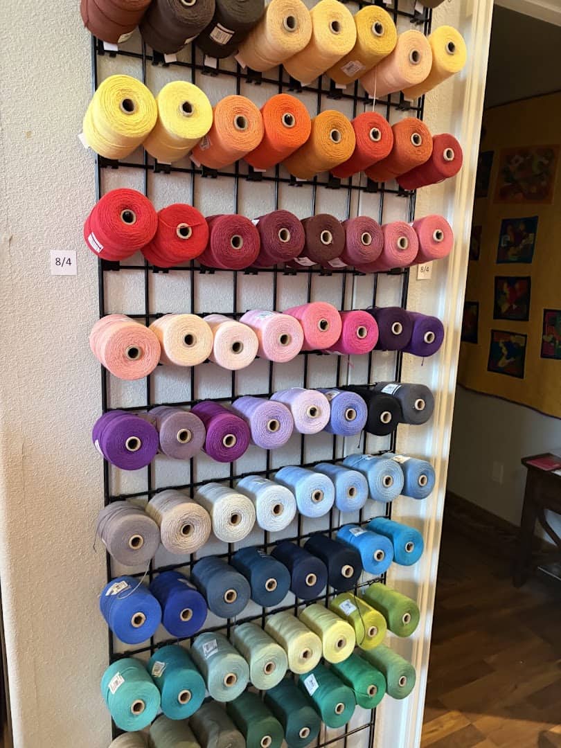 A rack of colorful thread and ribbon spools at The Quilted Skein in La Grange, Texas