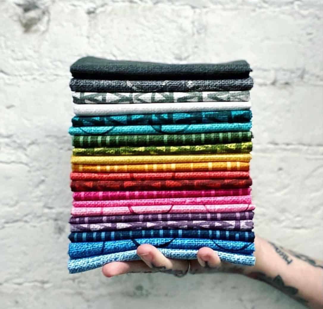 A stack of folded rainbow quilting fabric at The Sparkly Elephant Sewing Lounge in Friendswood, Texas