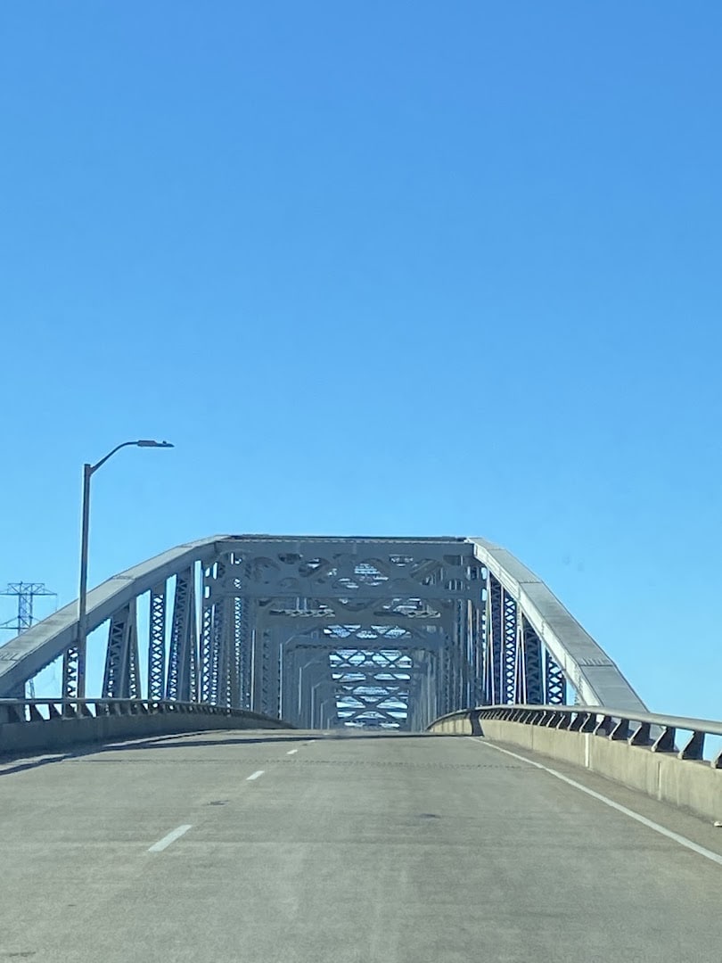 Curved steel arch of the Rainbow Bridge against a blue Texas sky