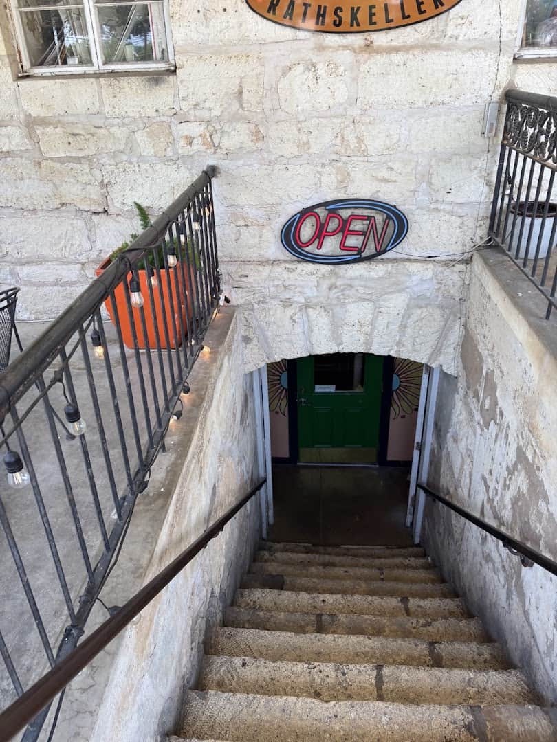 Stairs leading down to the green basement door of Rathskeller Bistro in Fredericksburg