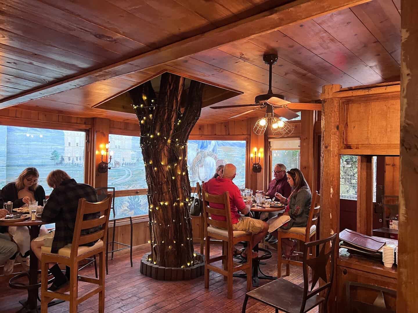 Dining room with a lit tree column and Western murals at Reata in Alpine, Texas