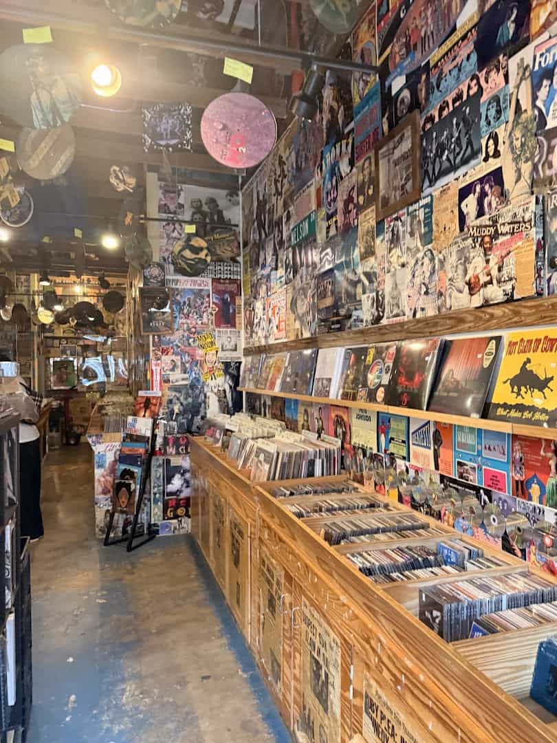 Record aisle with CD bins and a wall of music clippings at Sigs Lagoon in Houston