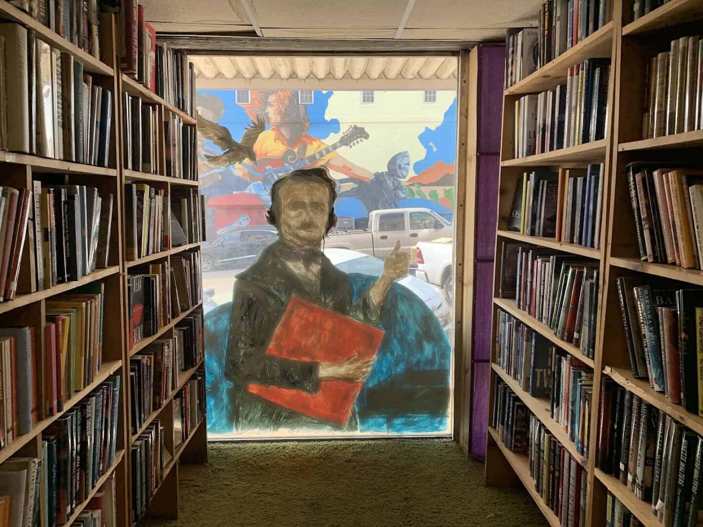 A quiet book aisle with wall art at Recycled Books in Denton, Texas