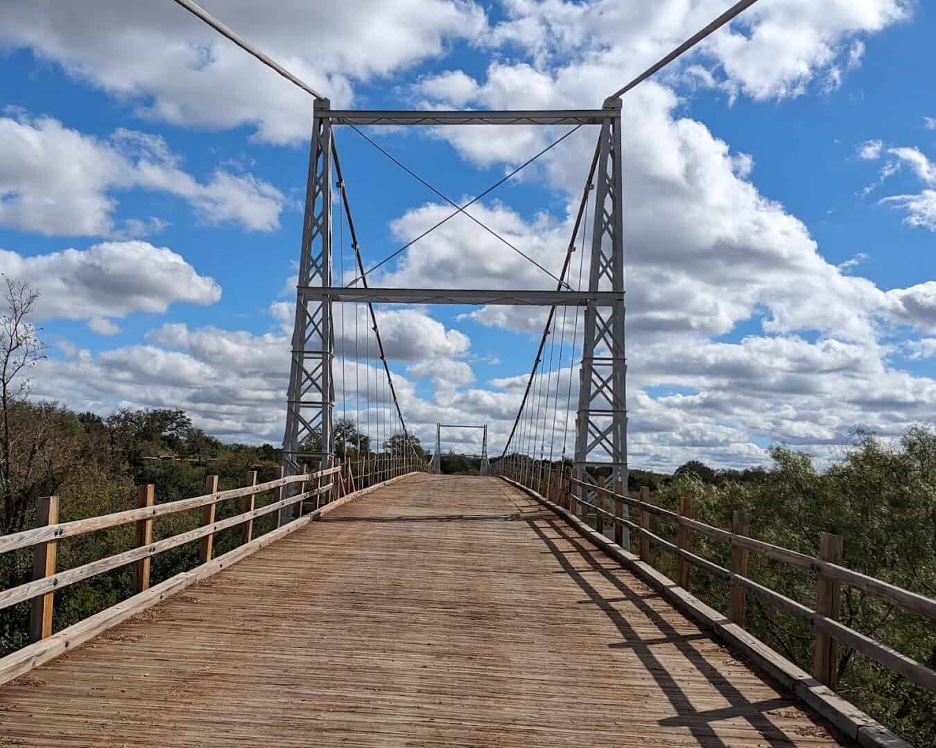 The Regency Suspension Bridge deck leading toward its steel tower under Texas skies
