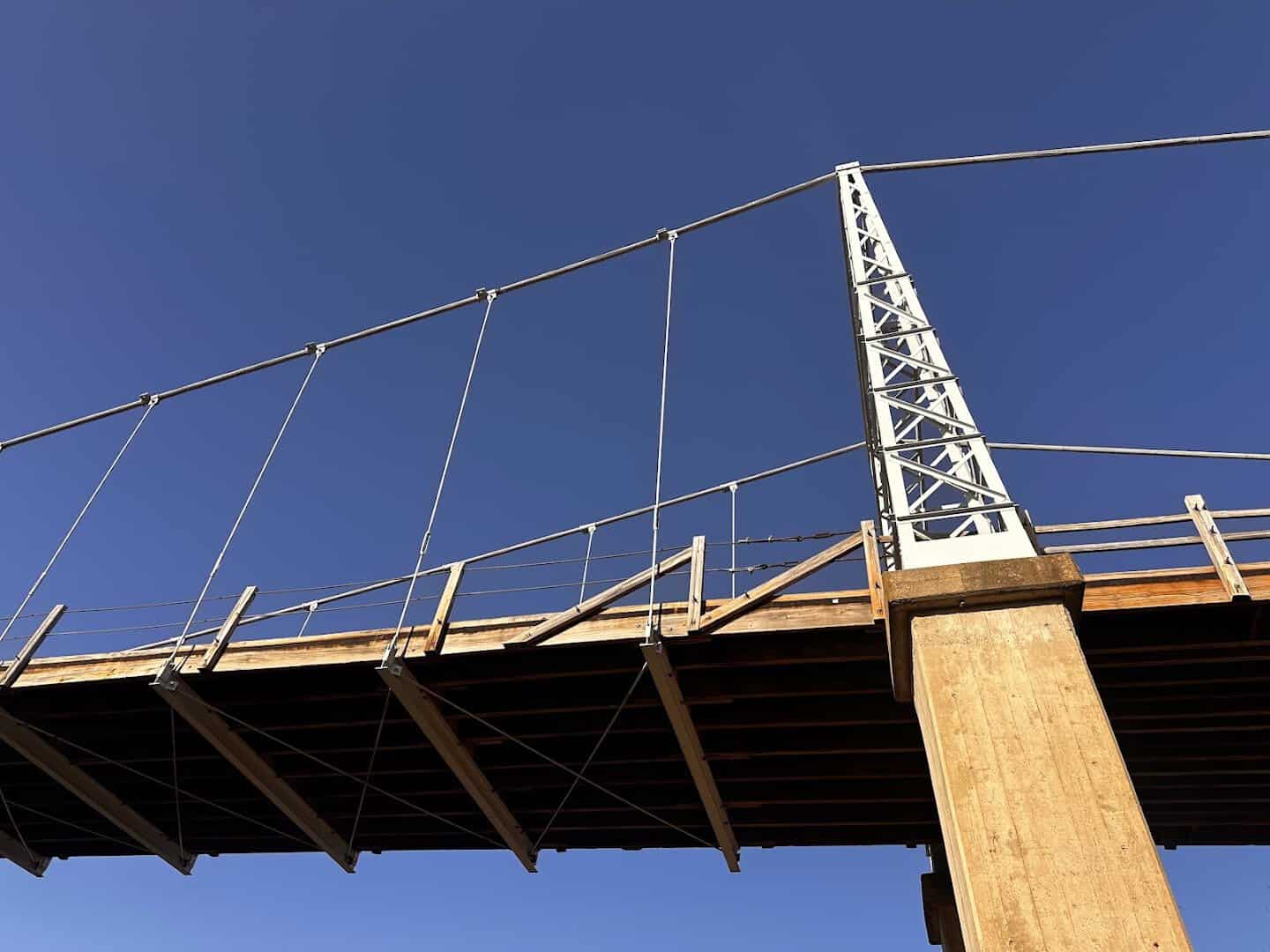 The steel tower of the historic Regency Suspension Bridge against a blue Texas sky