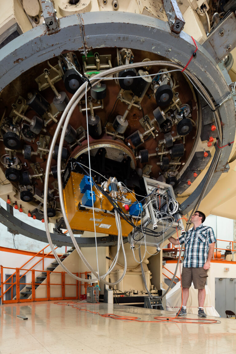 Visitor dwarfed by a large research telescope inside a dome at McDonald Observatory