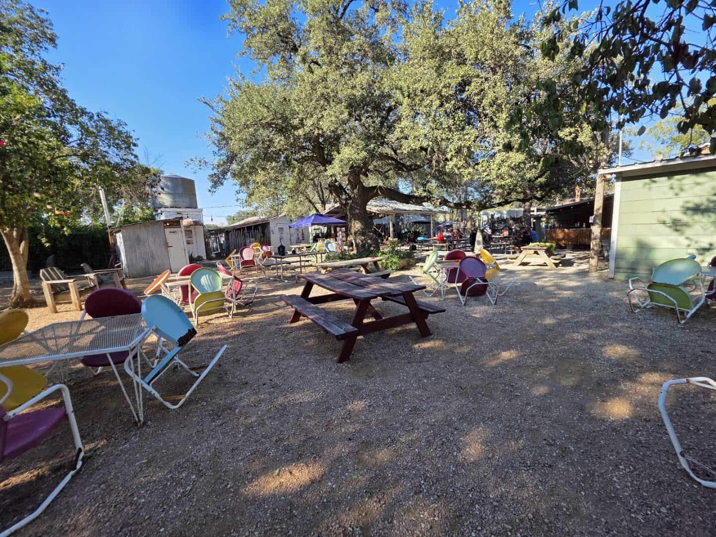 The shaded beer garden with picnic tables under oak trees at Riley's Tavern in Hunter, Texas
