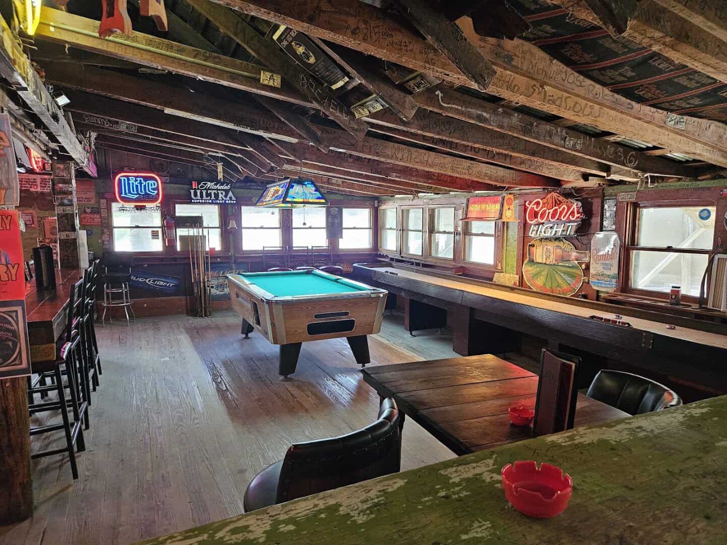Shuffleboard and pool tables under neon signs inside Riley's Tavern in Hunter, Texas