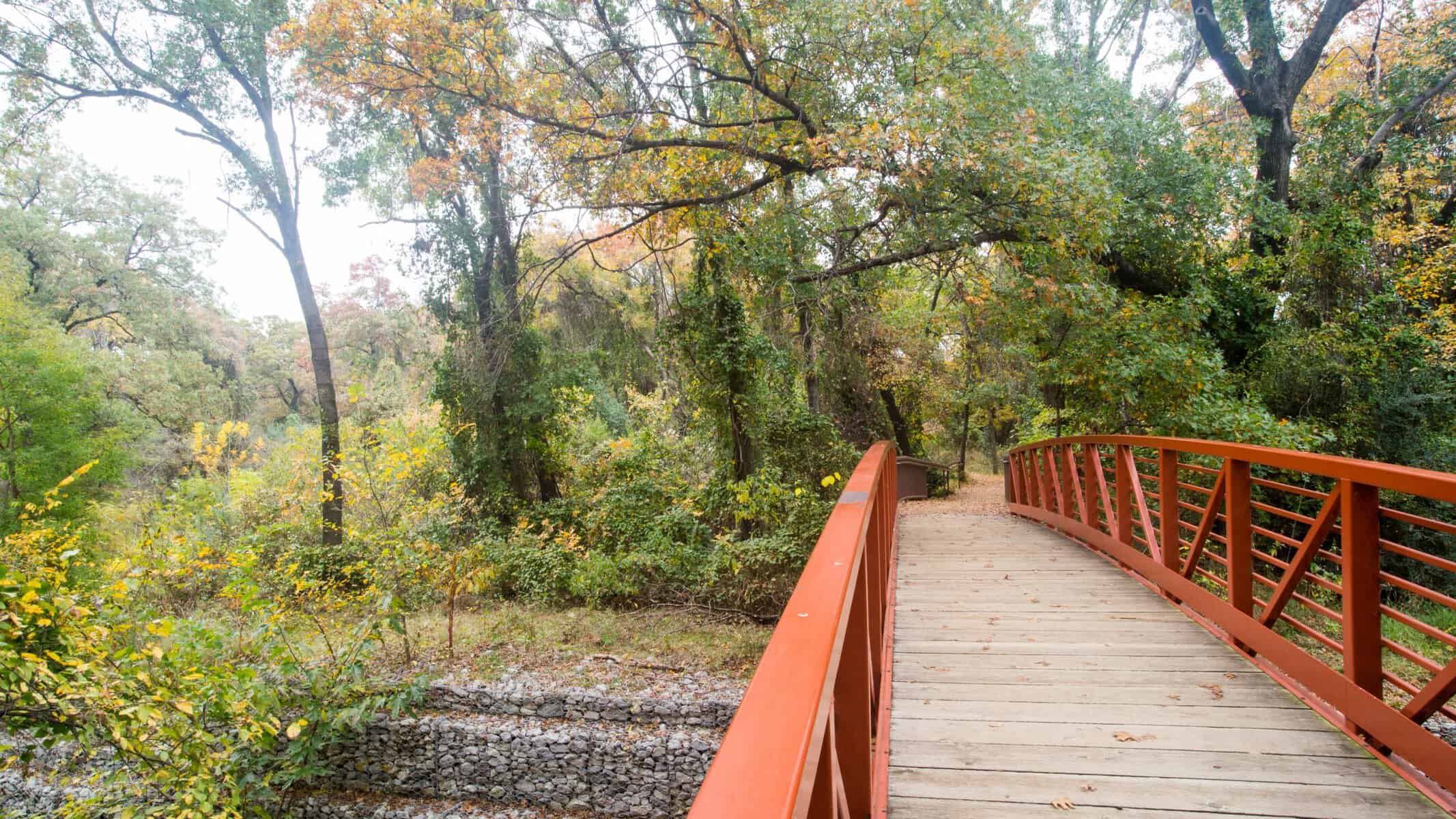 Shaded wooden boardwalk trail through the trees at River Legacy Park in Arlington