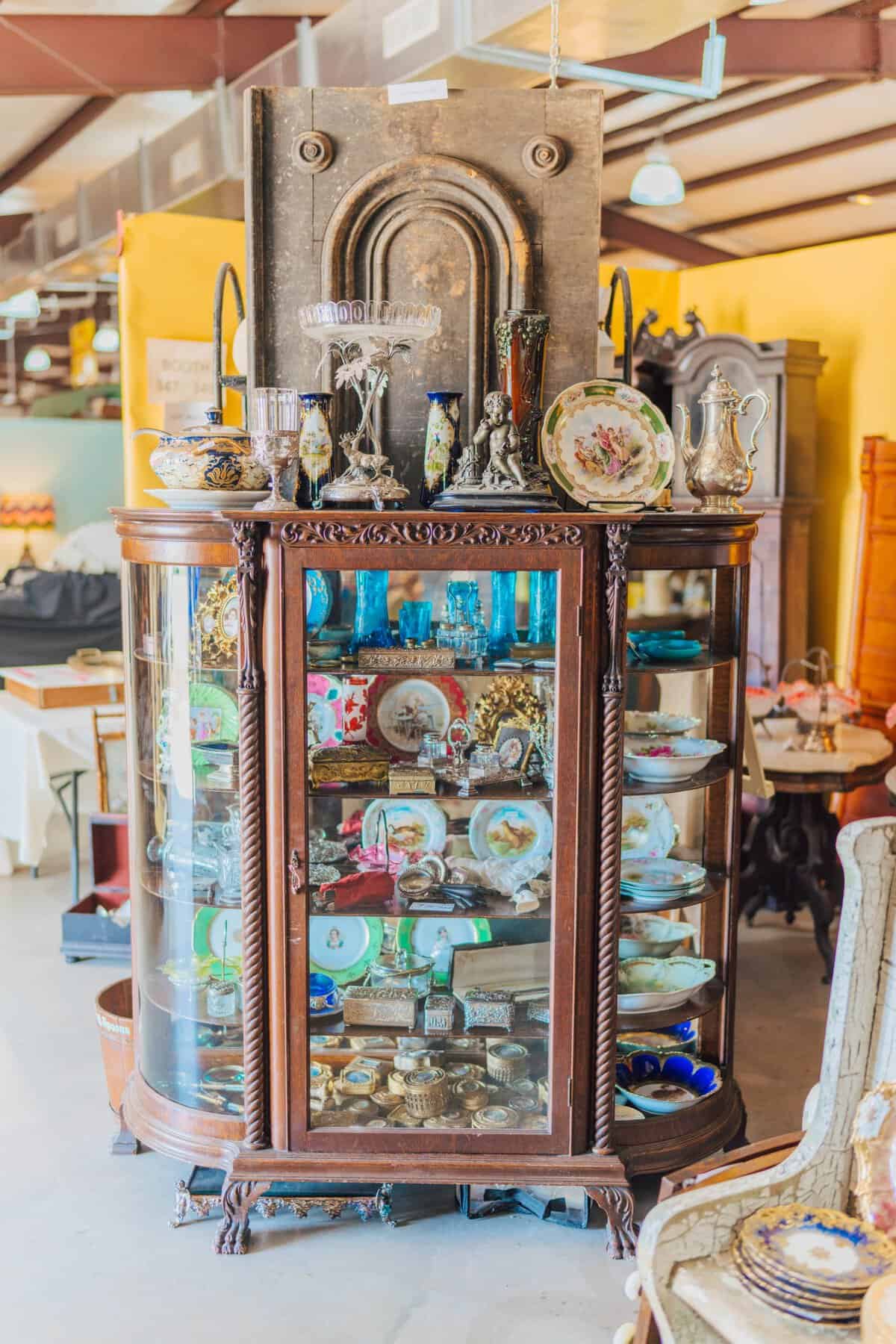 Antique curio cabinet filled with cut glass and collectibles at the Round Top antiques fair