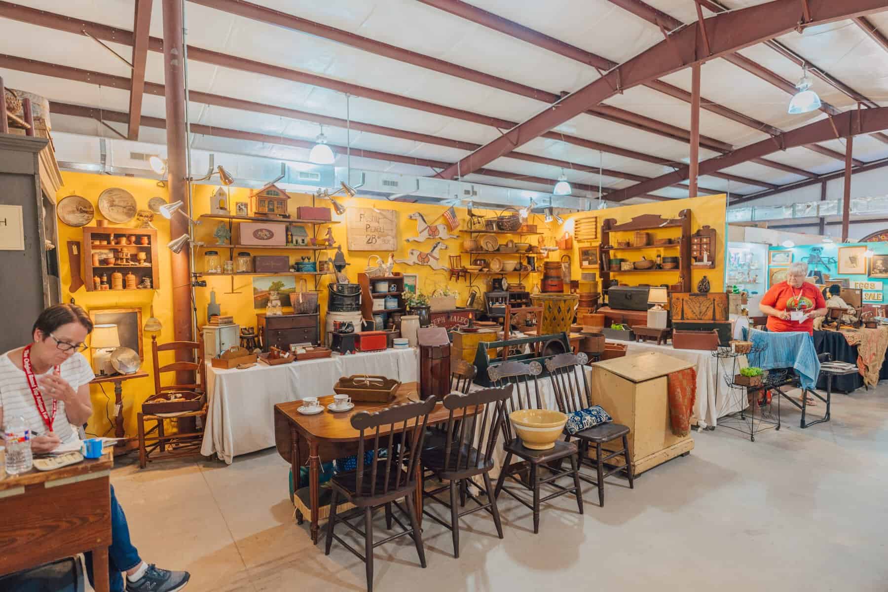 A vendor at an antique furniture booth inside the Round Top fair