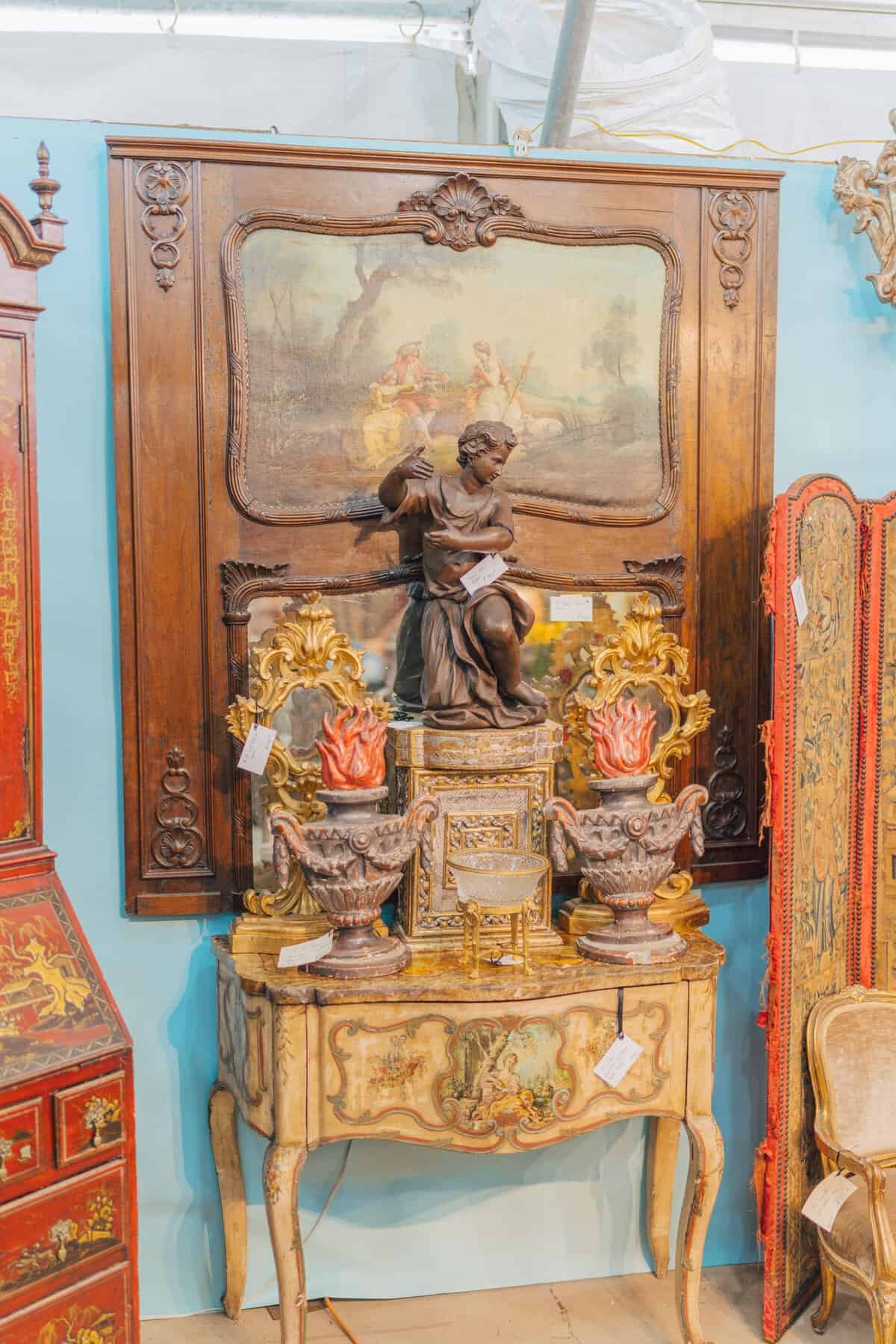 Ornate gilt antique cabinet with a bronze statue and mirror at the Round Top antiques fair