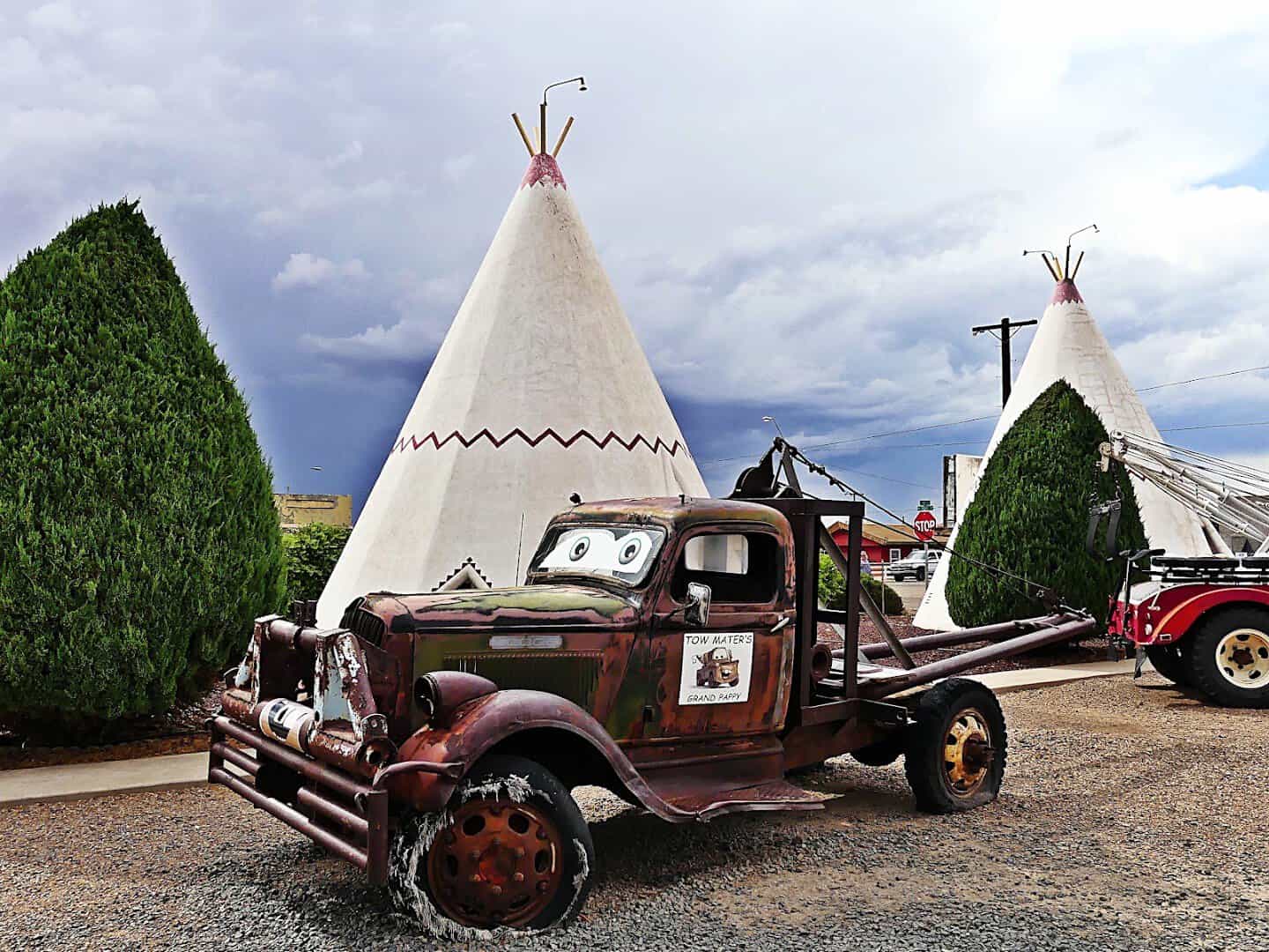 White teepee cabins rising against a dramatic sky with a vintage truck at the Wigwam Motel on Route 66 in Holbrook, Arizona
