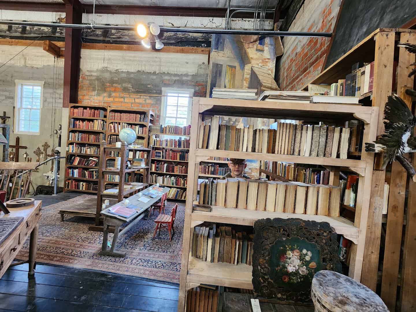 Rows of old books on wooden shelving in the book room at Carol Hicks Bolton Antiques in Fredericksburg