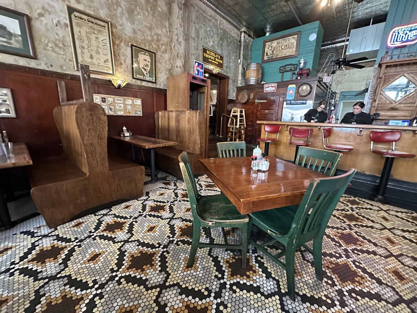 Historic dining room with wooden booths and tile floor at Schilo's in San Antonio