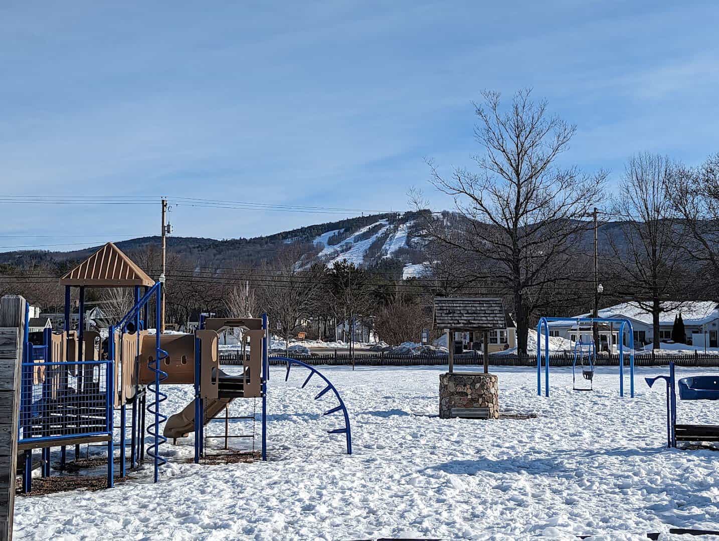 Snow-covered Schouler Park with a playground and the ski trails of Cranmore Mountain behind, North Conway, New Hampshire