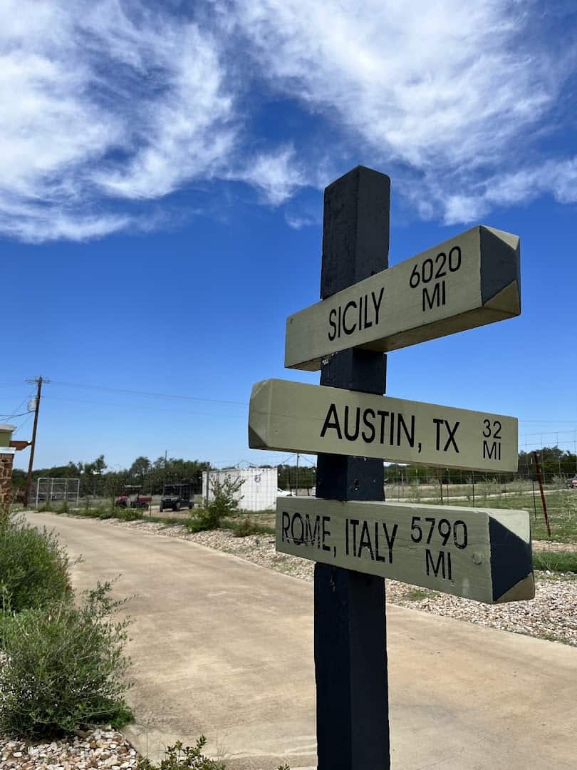 Directional signpost to Sicily, Austin, and Rome at the olive farm