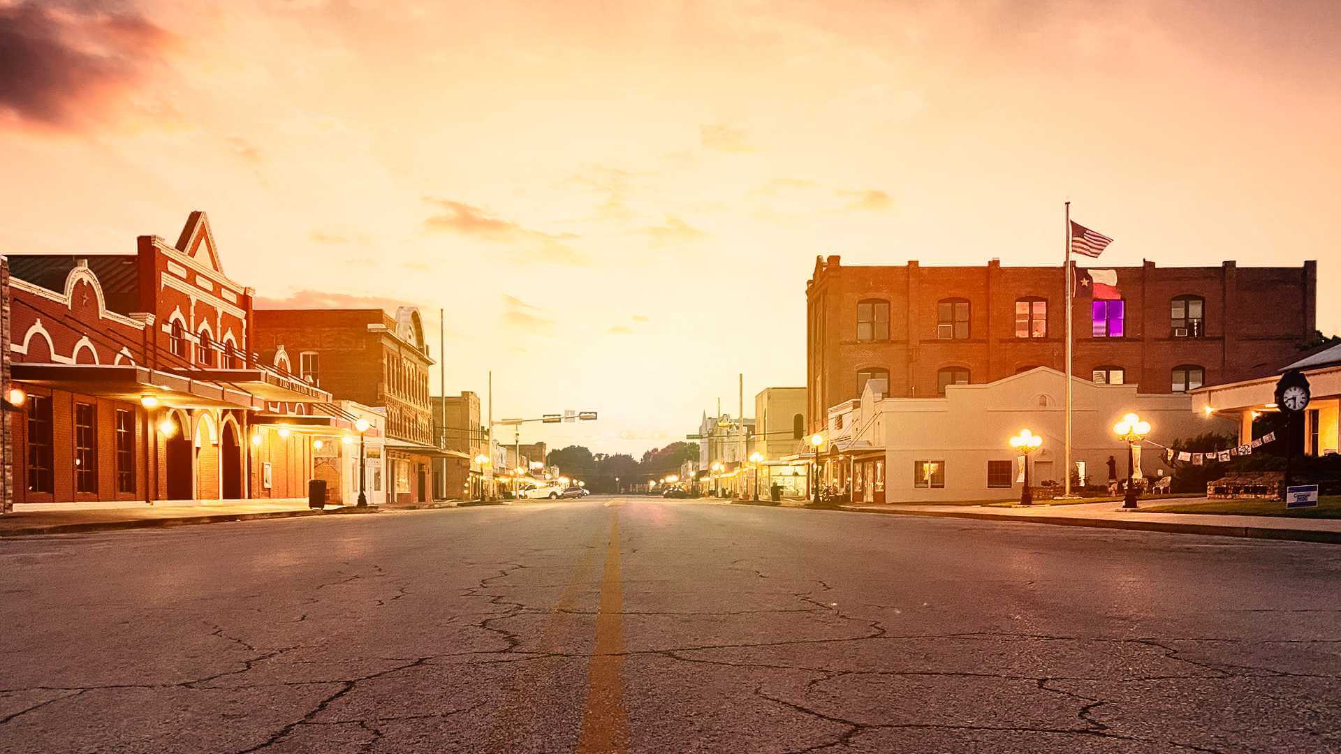 Brick storefronts along Main Street at dusk in downtown Smithville, Texas