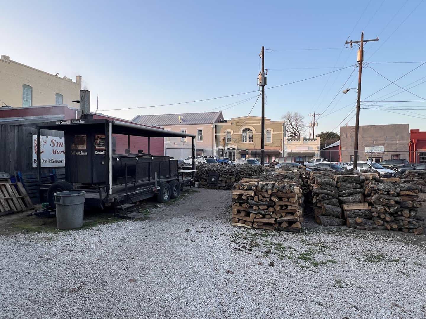 Stacked post oak firewood and open smoker pits at Smitty's Market in Lockhart, Texas